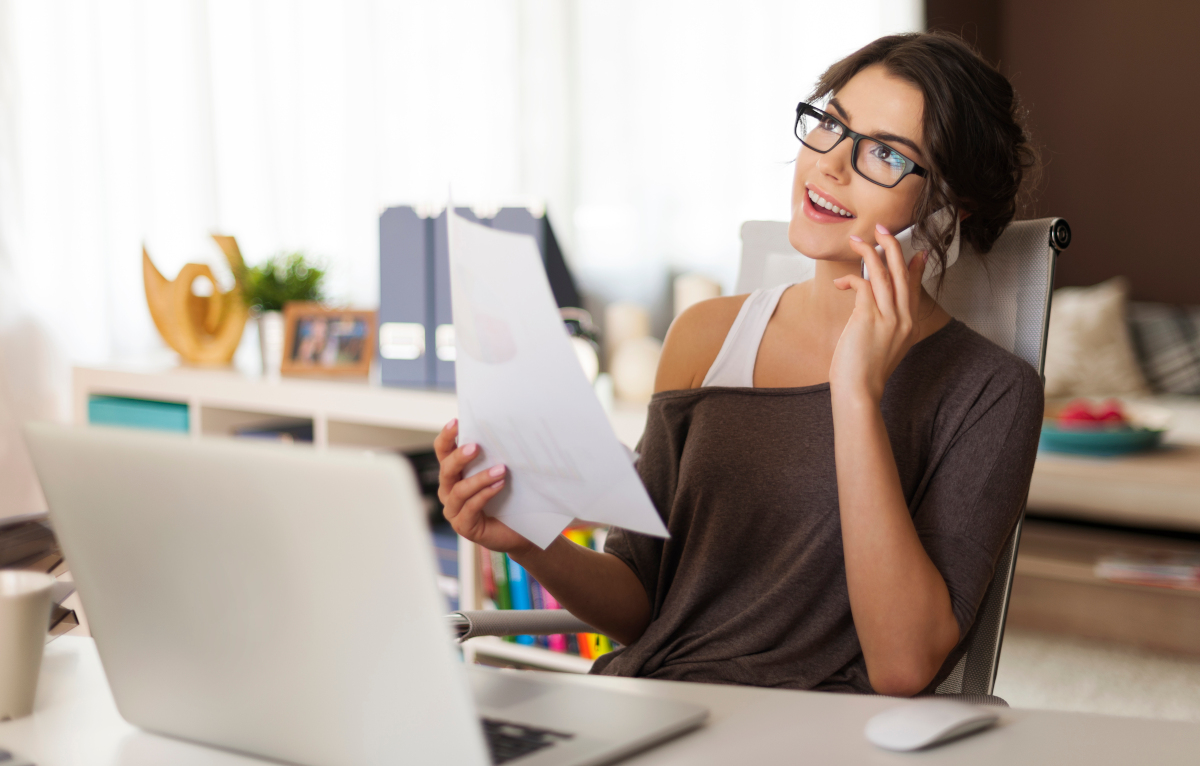Woman working on laptop and talking on phone